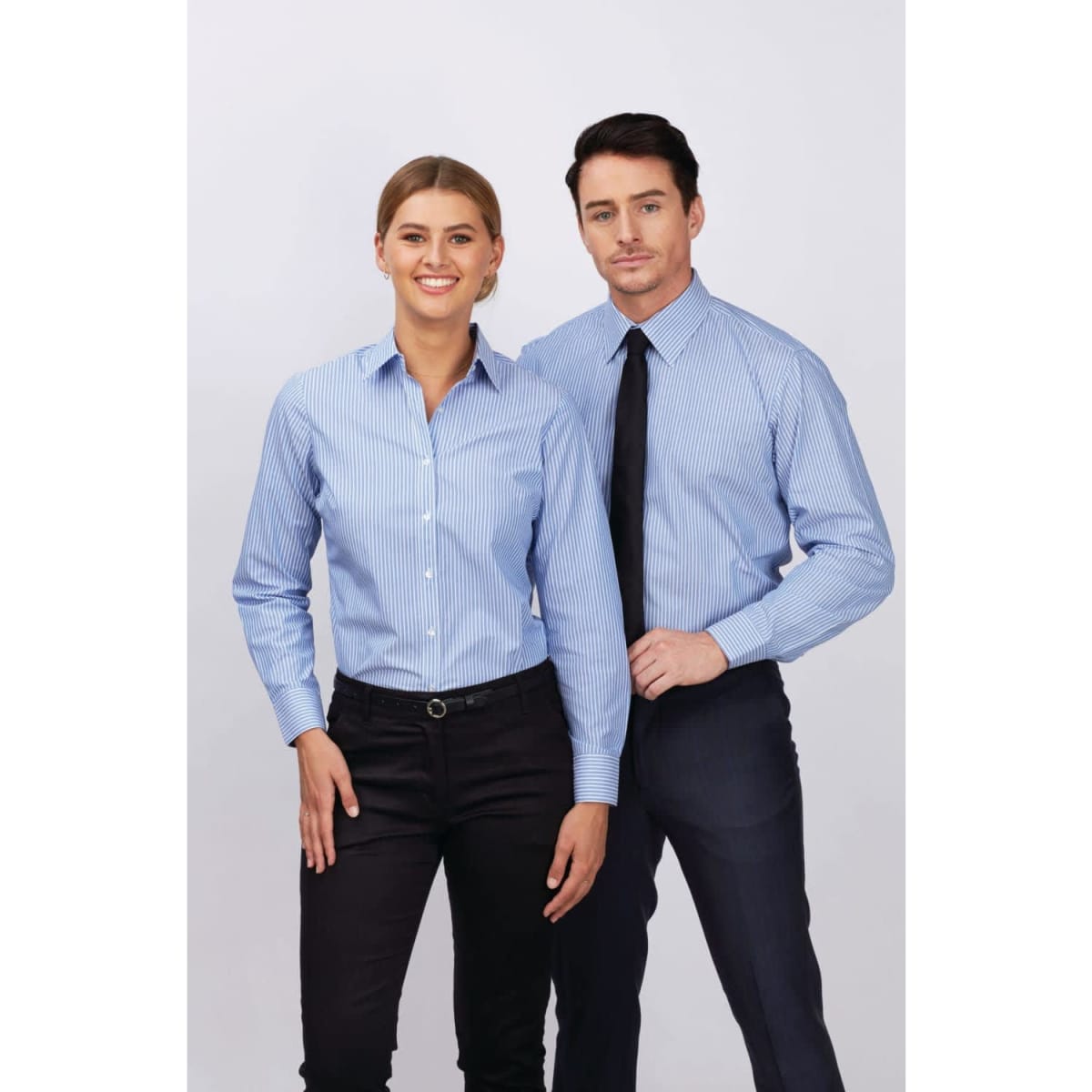A ladies’ long sleeve button-up shirt in light blue with white stripes, worn by a model next to a man in a tie.