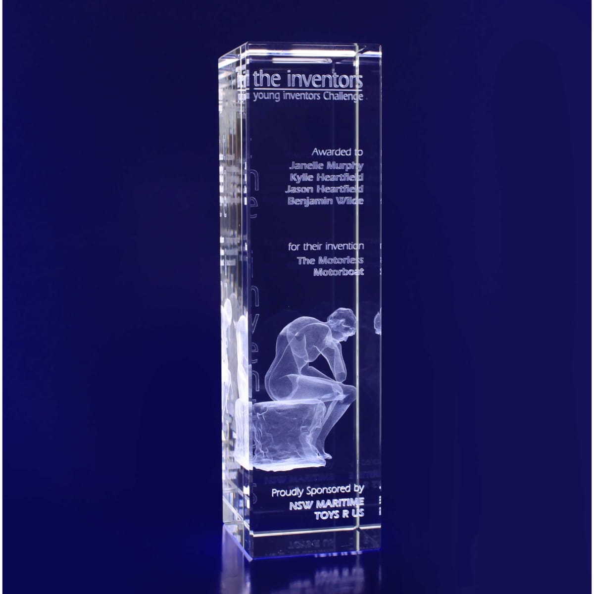 A crystal rectangle trophy featuring a carved figure in contemplation, showcasing a logo and award details. Clear and luminous.
