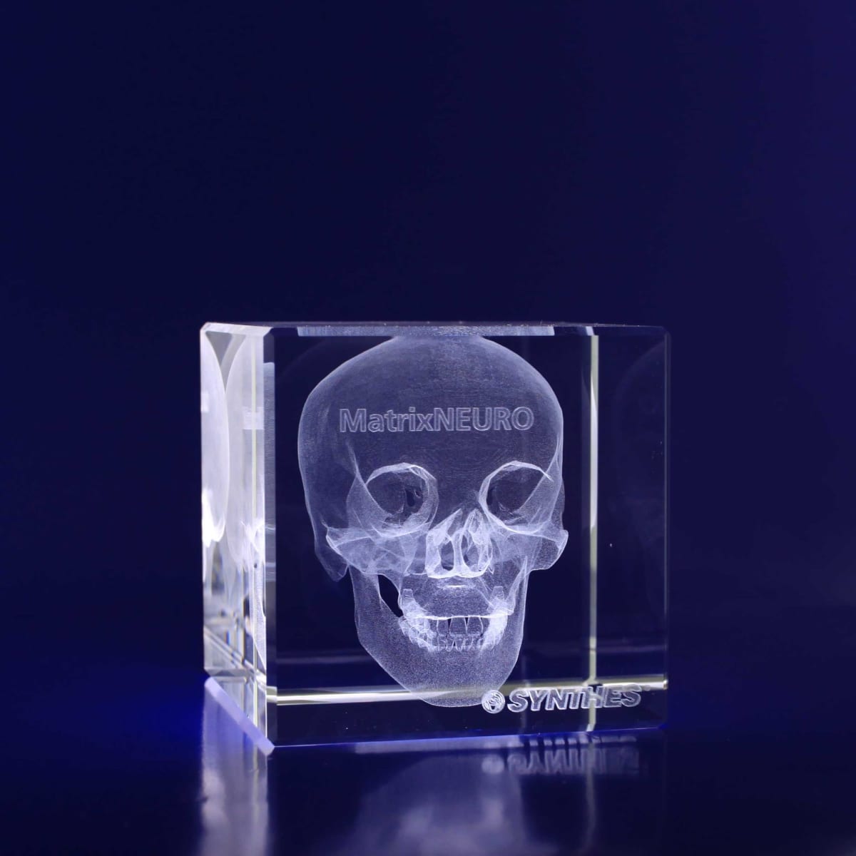 A clear 3D crystal cube featuring an engraved skull design, displayed against a dark background.