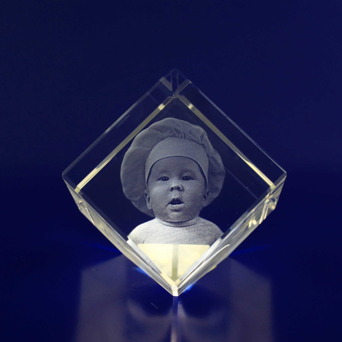 A 3D crystal diamond displaying a monochrome image of a baby wearing a chef's hat, set against a dark background.