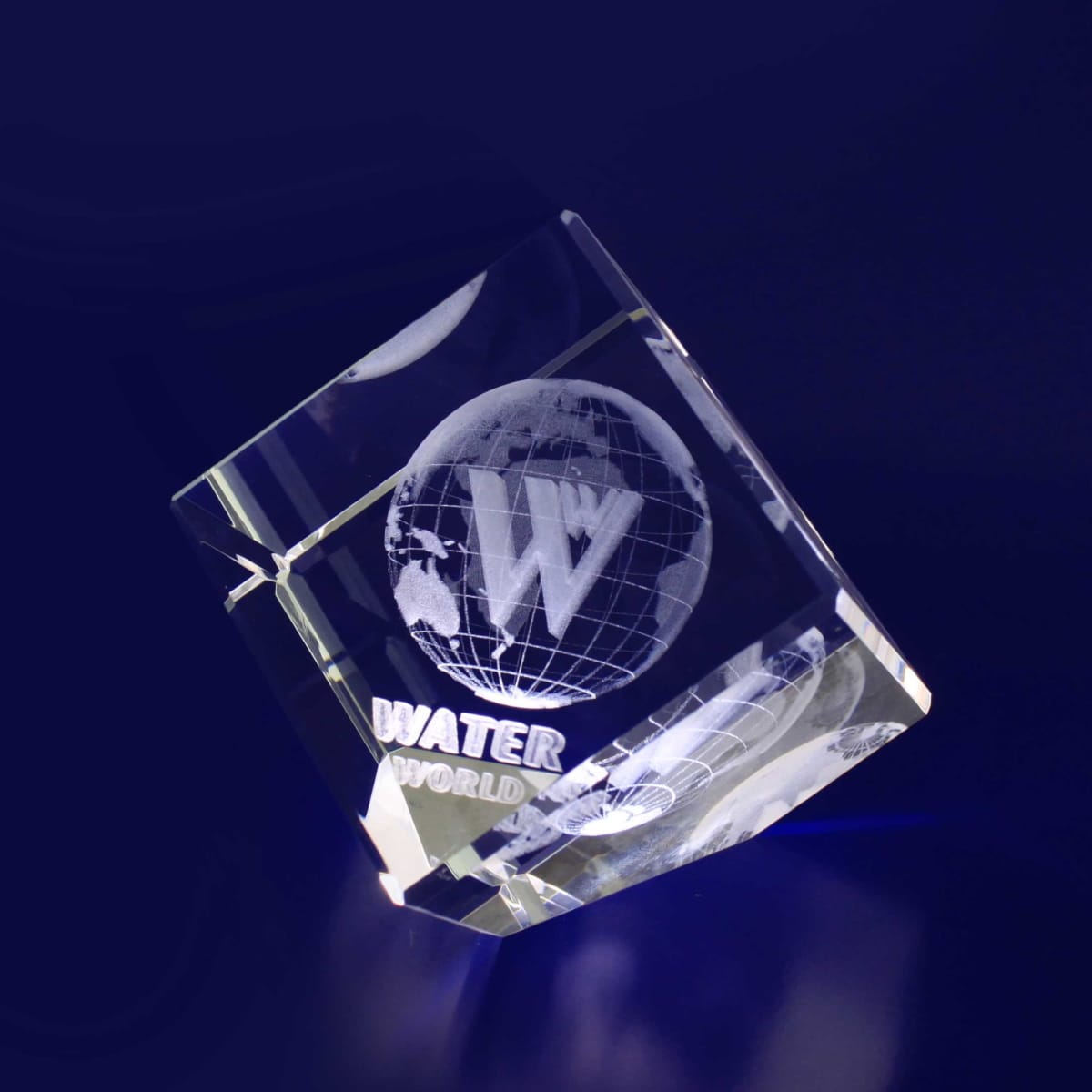 A clear crystal diamond with a globe design and a logo, resting on a dark blue background.