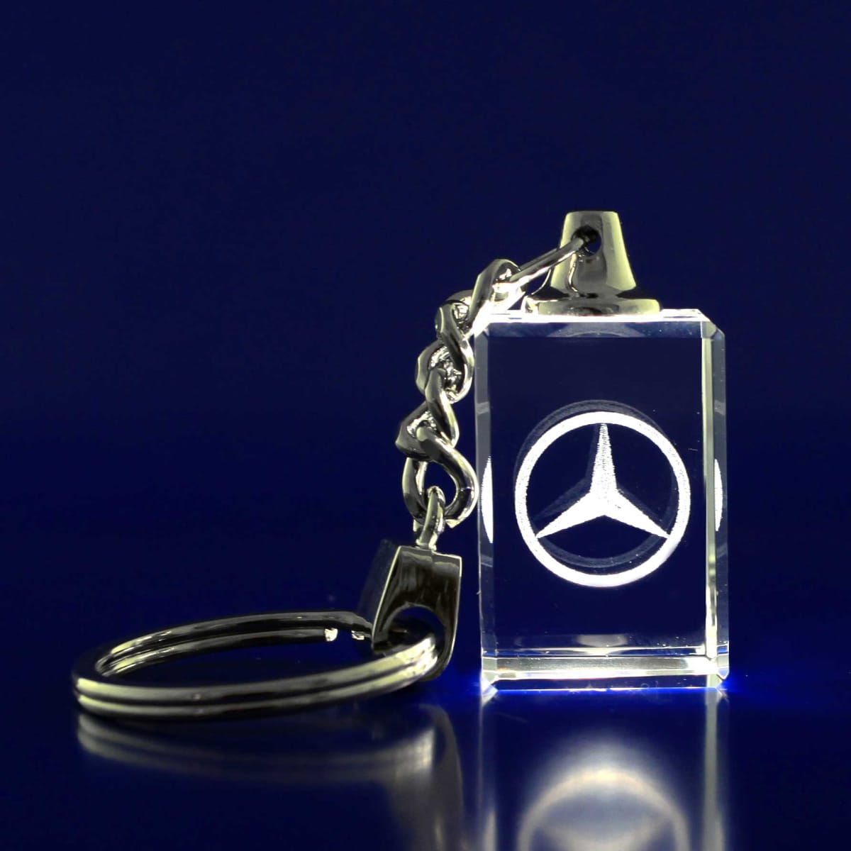 A 3D crystal keyring featuring a silver logo, attached to a metallic chain, on a blue background.