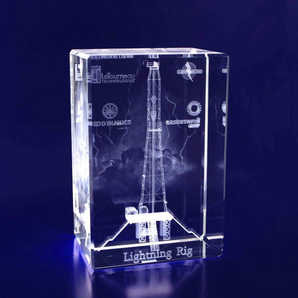 A clear 3D crystal rectangle monolith featuring a detailed etched design of a drilling rig against a stormy background.