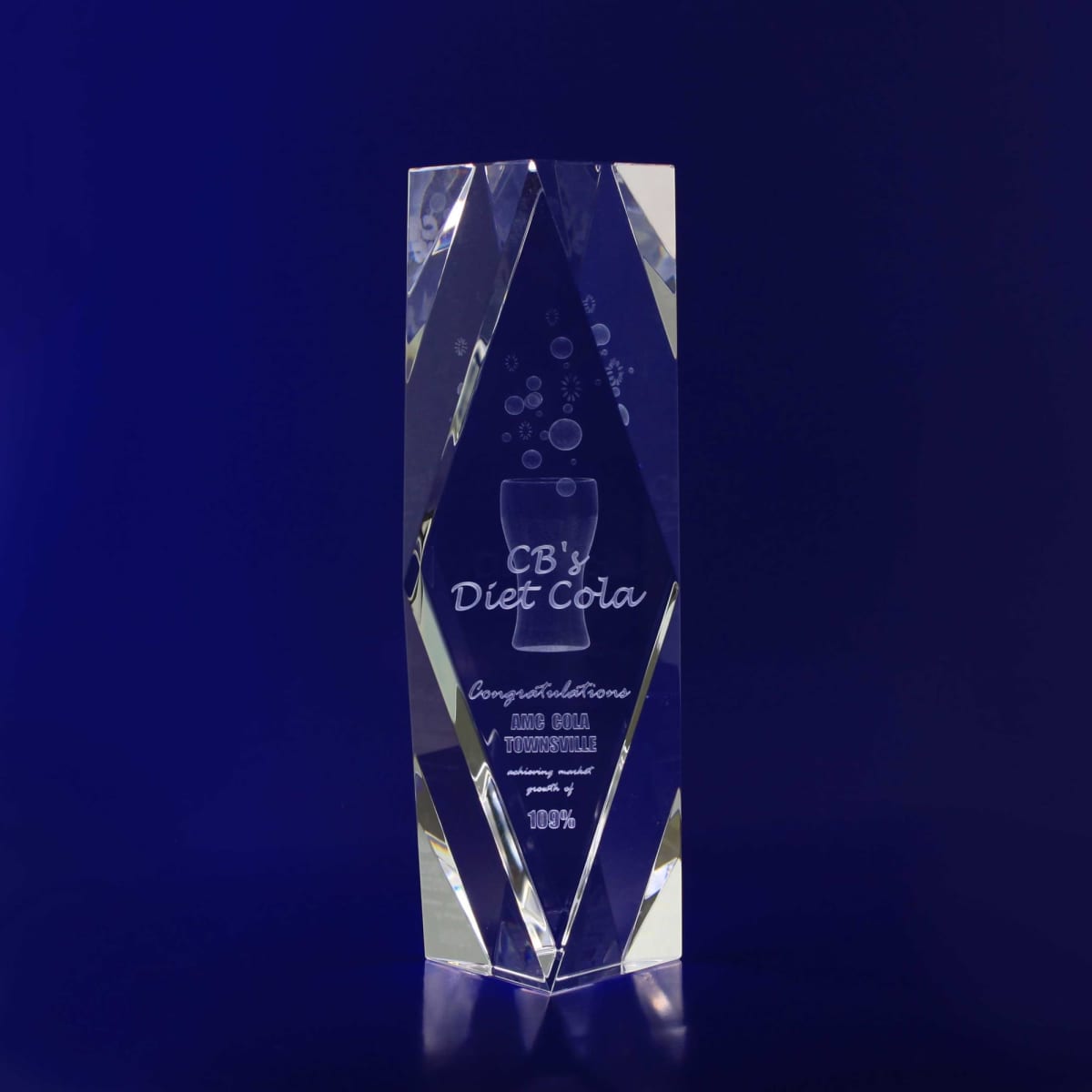 A clear crystal trophy in a rectangular bevel tower design, featuring engraved text and a logo.