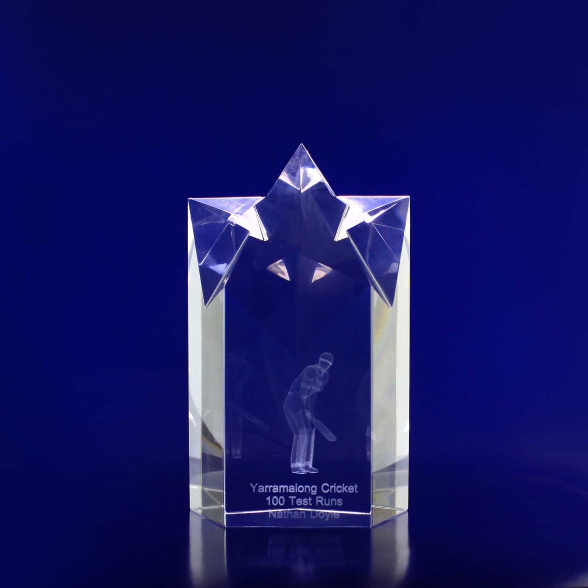 A clear crystal trophy in the shape of a star, featuring engraving and a logo. It reflects light beautifully.