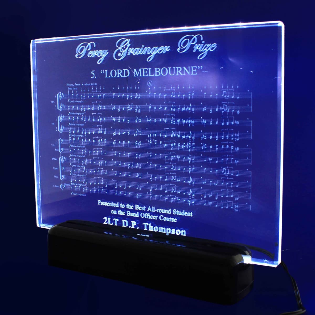 A clear 3D crystal plaque featuring music notation, mounted on a black base.