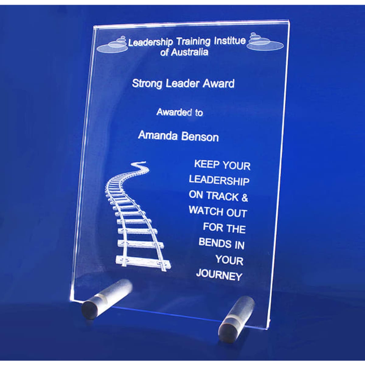 A clear acrylic plaque featuring a train track design with a stand. It has a logo and award text.