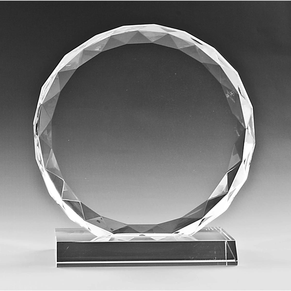 A clear crystal trophy with a circular, faceted design and a rectangular base.
