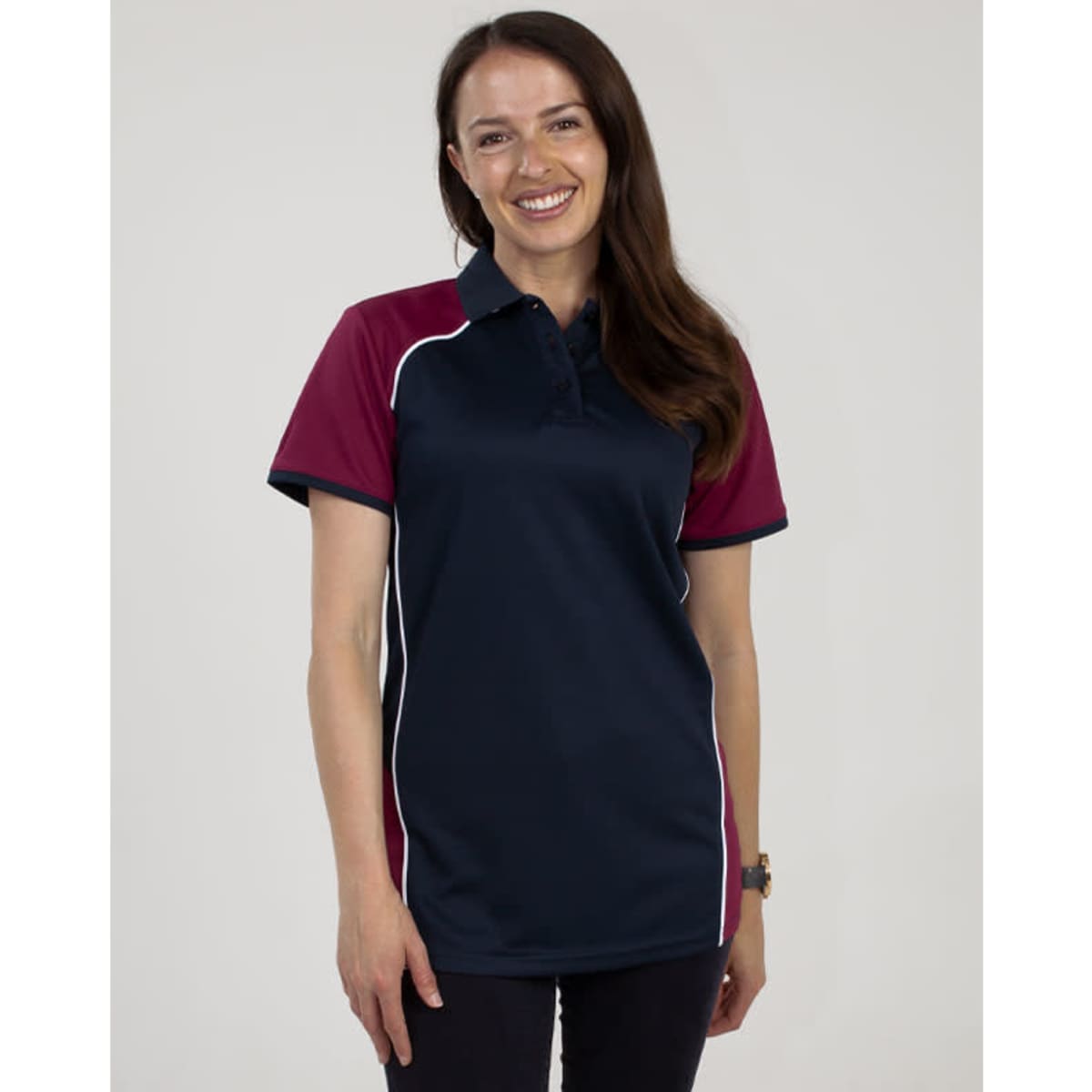 A woman wearing a navy and maroon polo shirt featuring a logo. The shirt has short sleeves and white piping.