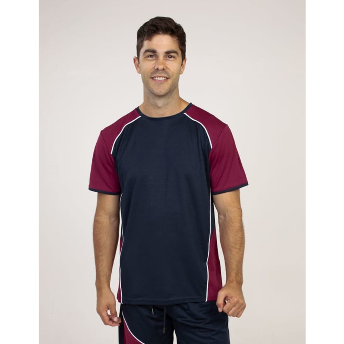 A blue and maroon T-shirt with contrasting piping, featuring a model smiling in a plain background.