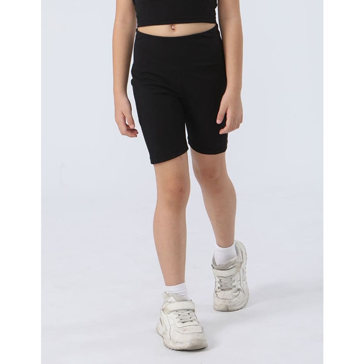 Black girl's legging shorts with a fitted design, paired with white sneakers, set against a light background.