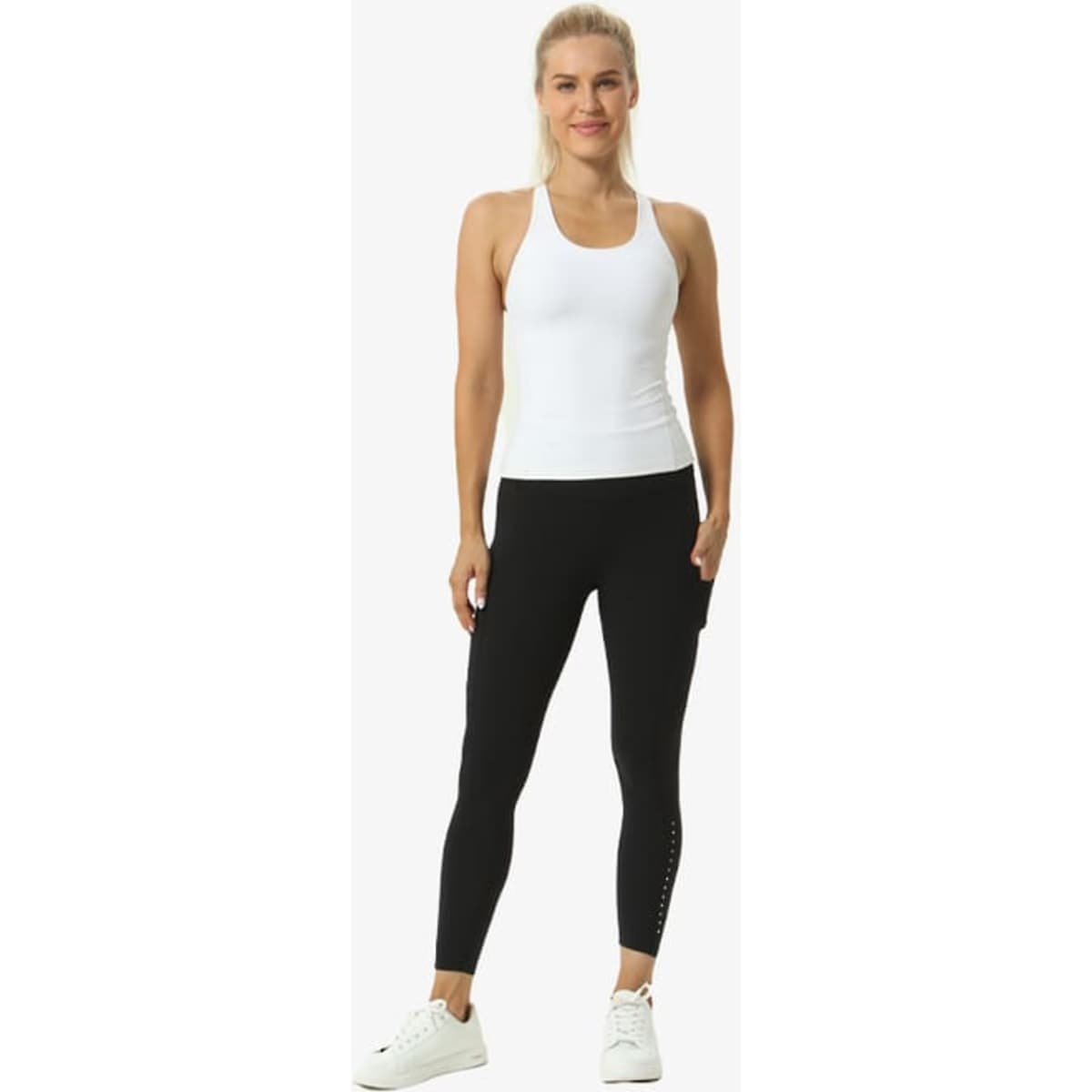 A person in a white top and black leggings performs a yoga pose against a plain background. The leggings feature a logo.