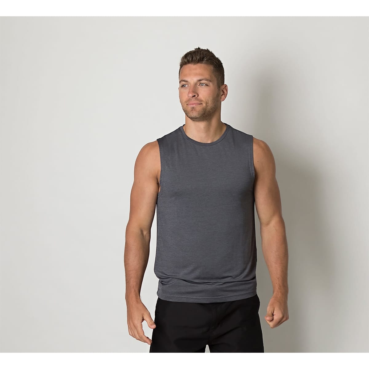 A grey sleeveless shirt is worn by a man standing against a plain background. The shirt features a logo.