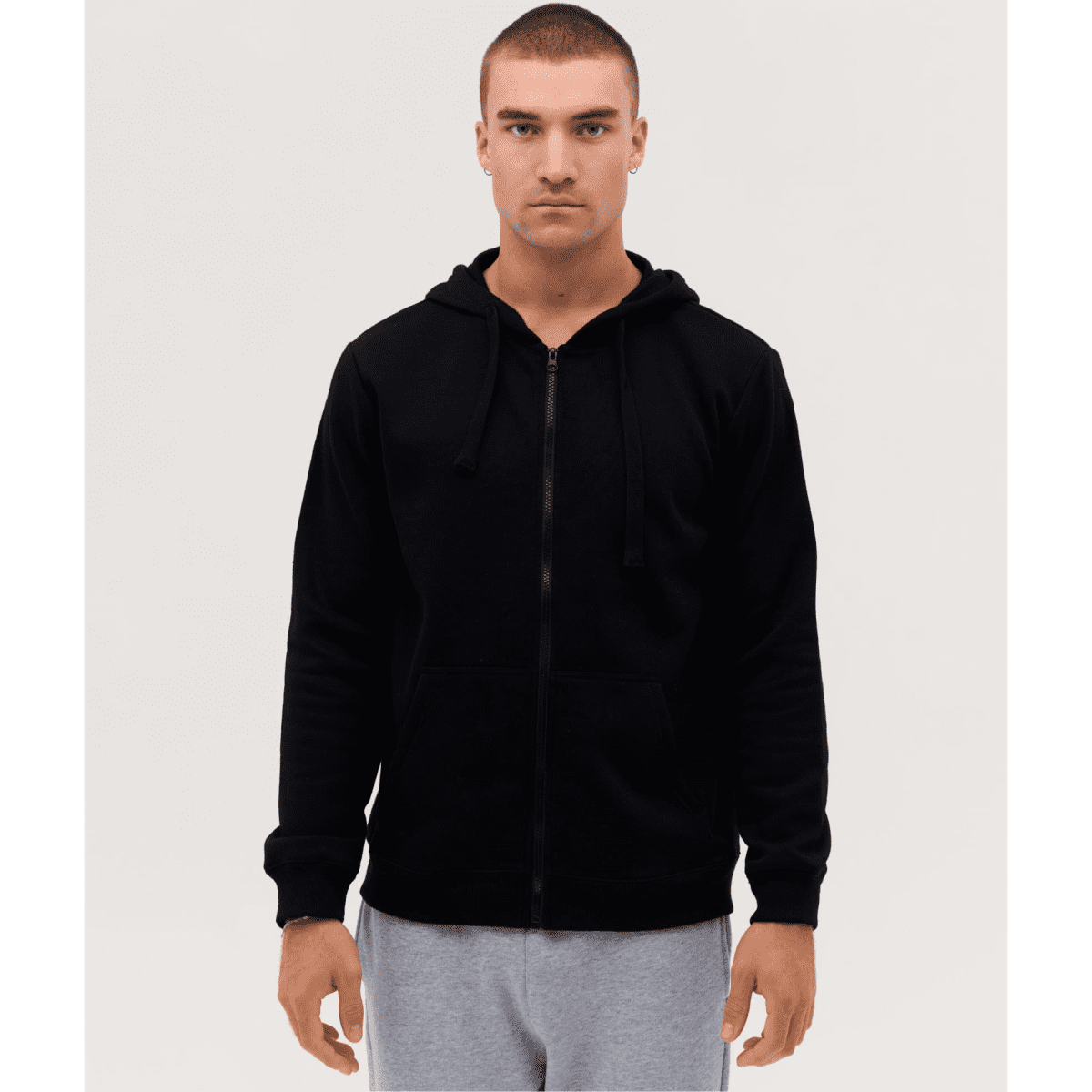 A black zip-up hoodie with a front pocket and adjustable hood, modelled by a person standing against a plain background.