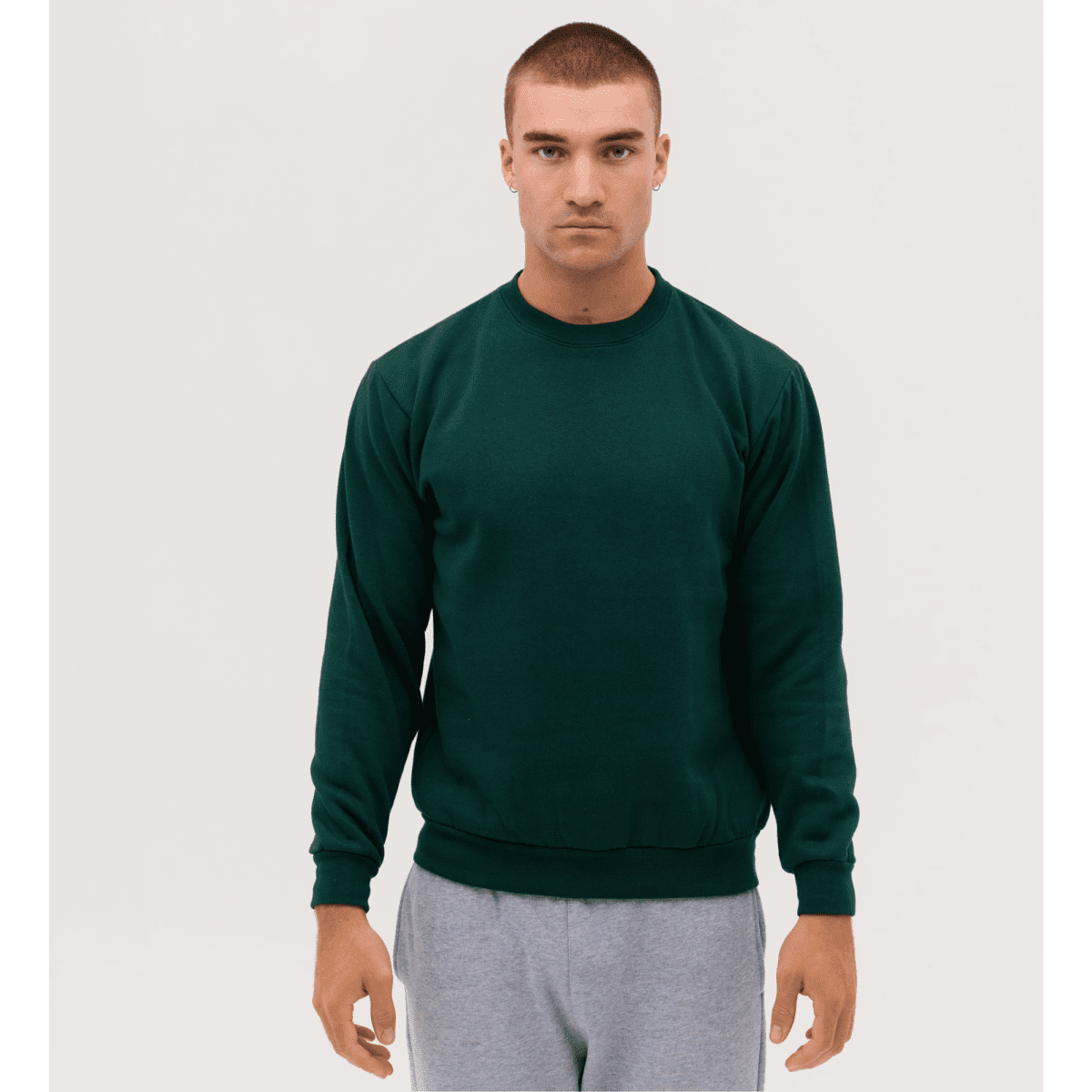A green crew neck sweatshirt, worn by a model with a neutral expression, styled with grey sweatpants.