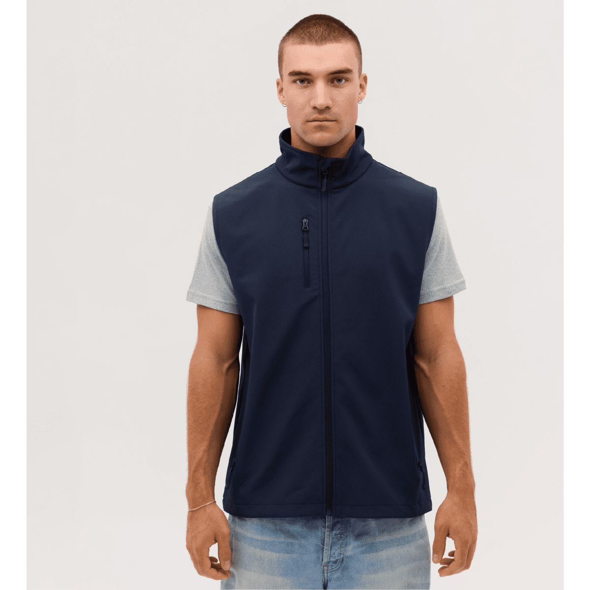 A navy softshell vest is worn over a grey short-sleeved shirt, featuring a zip closure and a pocket.