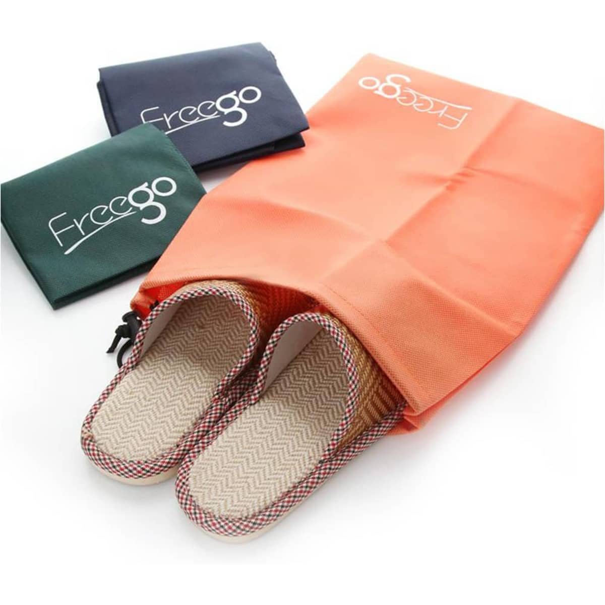 An orange drawstring pouch with slippers peeking out, accompanied by two flat bags in navy and green.
