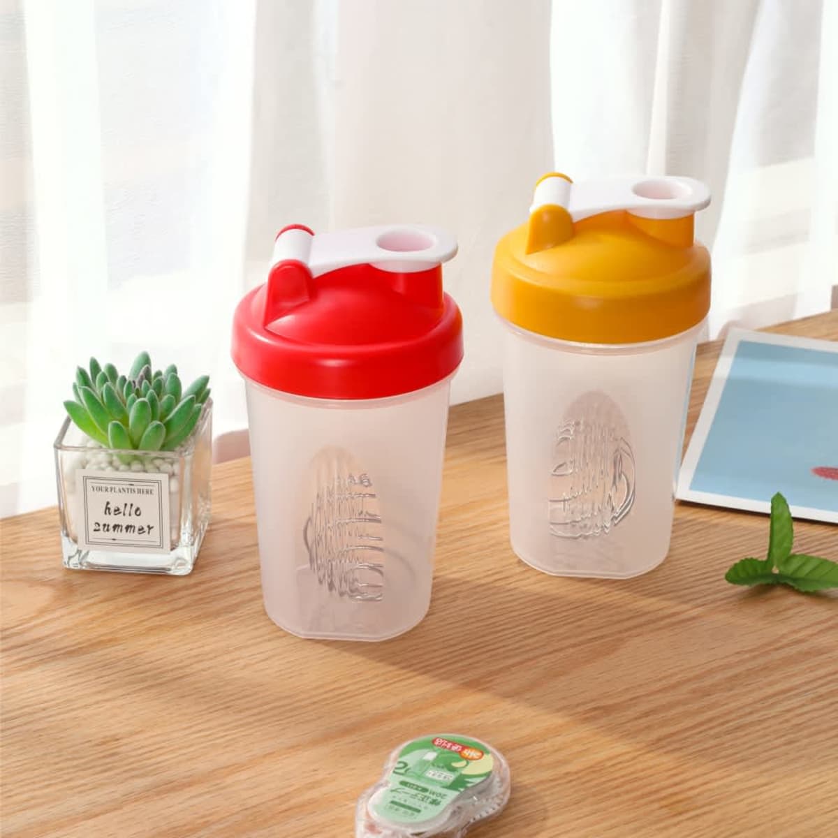 A drink bottle set featuring a red shaker and a yellow shaker, both with screw-on lids and a logo.