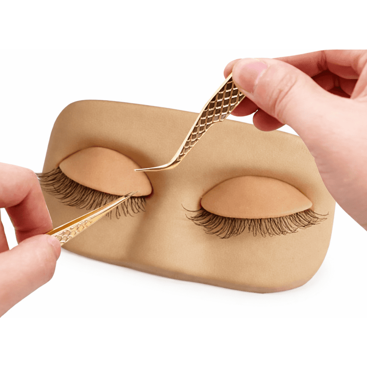 A practice lash extension training pad featuring two realistic eyelids with eyelashes, being used with tweezers.