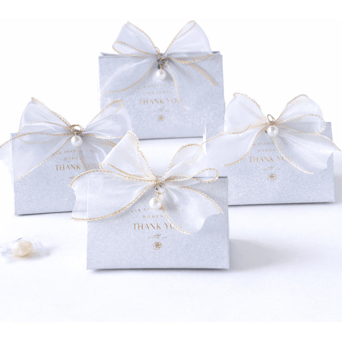 Four grey gift boxes adorned with white bows and gold ribbon, featuring pearl embellishments and "Thank You" text.