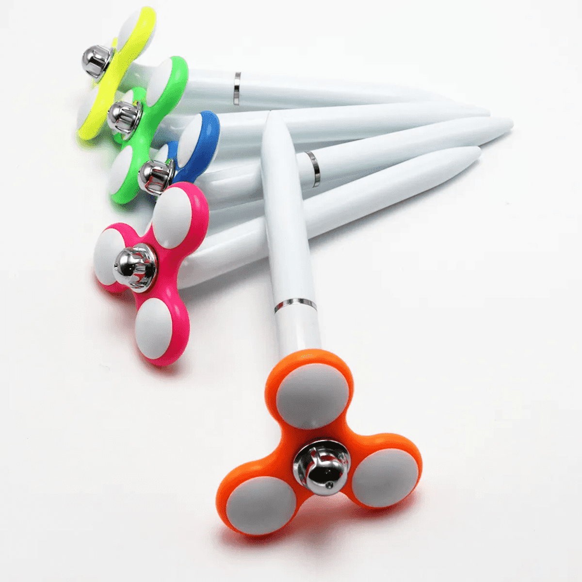 A collection of hand spinner pens in various colours: green, blue, pink, orange, and yellow, with white accents.