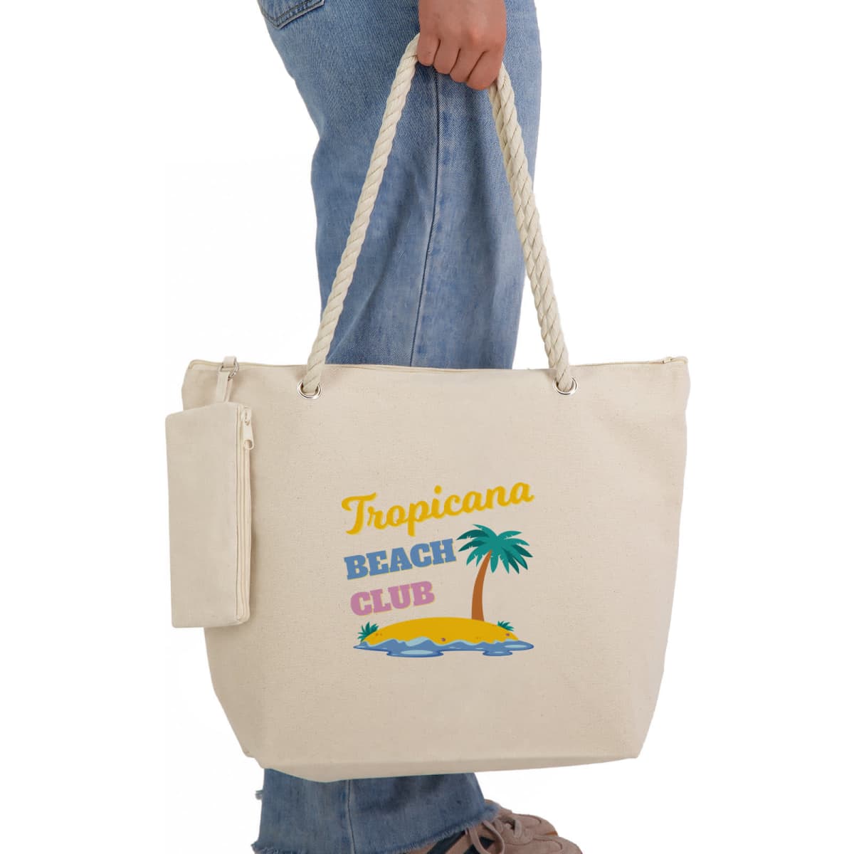A creamy beige tote bag with a rope handle, featuring a tropical beach design and a detachable pouch.