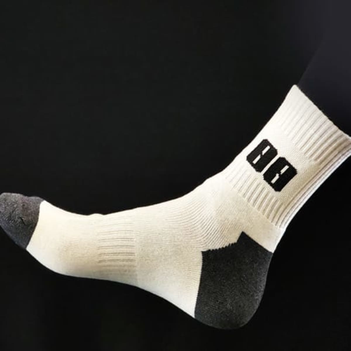 A pair of cotton quarter cricket socks in white with grey accents, featuring a black logo on the side.