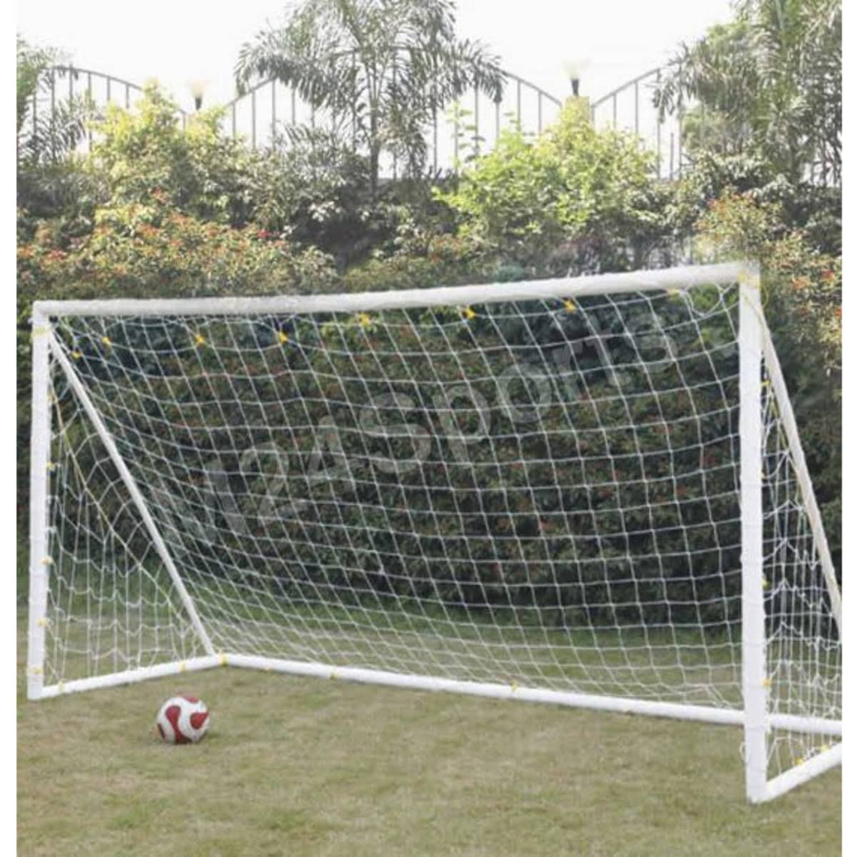 A white soccer goal post with a net stands on grass, accompanied by a red and white soccer ball nearby.
