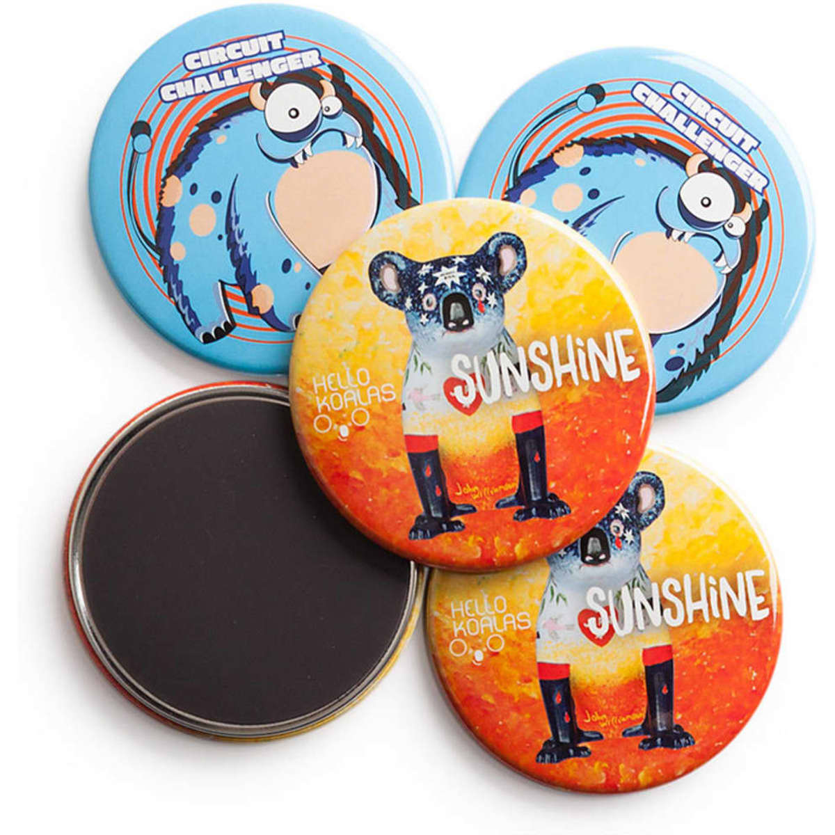 Four 64mm round magnets in various colours, featuring cartoon designs and a koala illustration. One magnet has a plain black back.