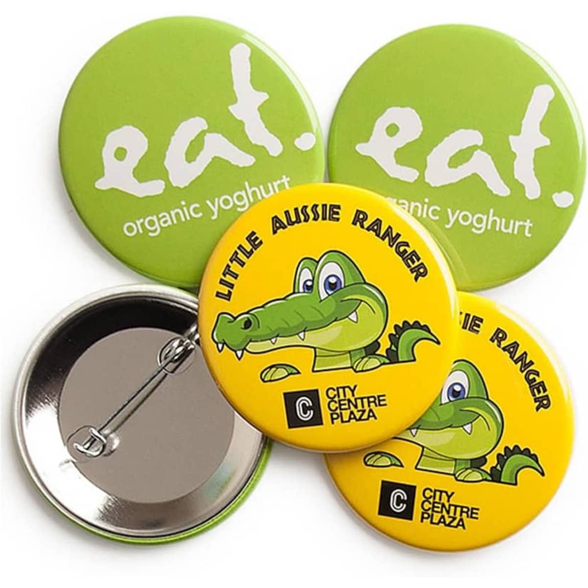 Four round badges, two in bright green with a logo, and two yellow with a cartoon crocodile design.