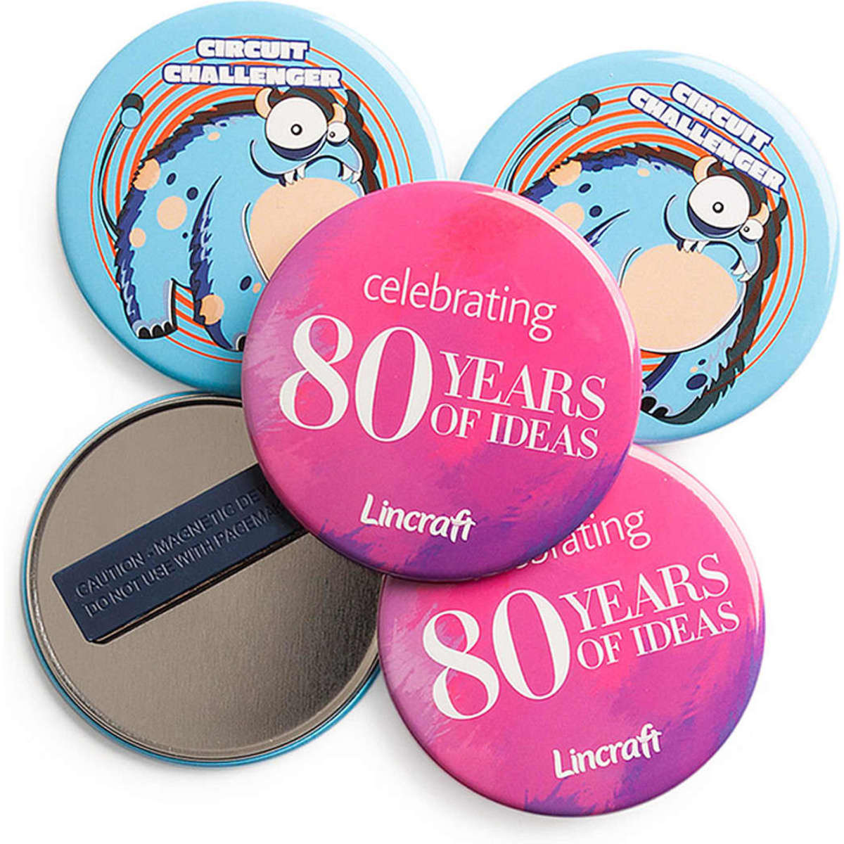 Four round badge magnets in vibrant blue and pink with various designs, including a logo and text about celebrating ideas.