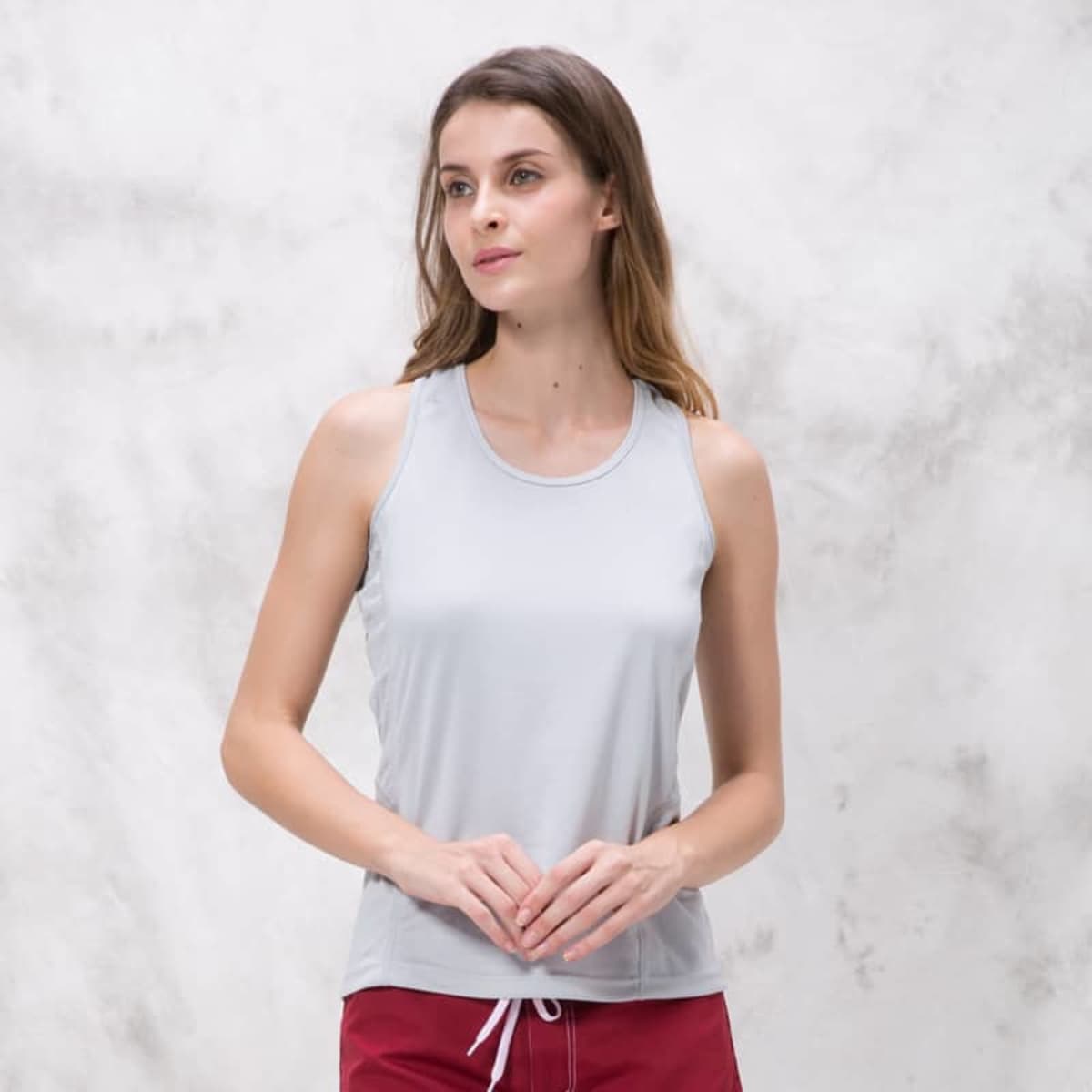 A light grey singlet with a relaxed fit, featuring a logo on the side and worn by a model.
