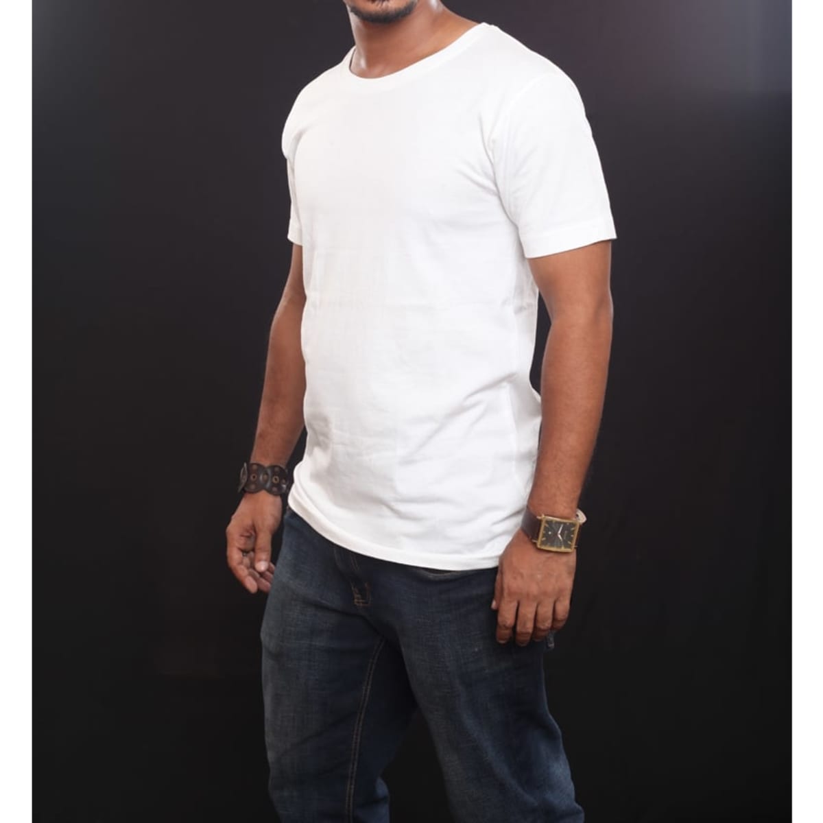 A white t-shirt displayed on a person wearing jeans, featuring a simple design and a logo on the chest area.