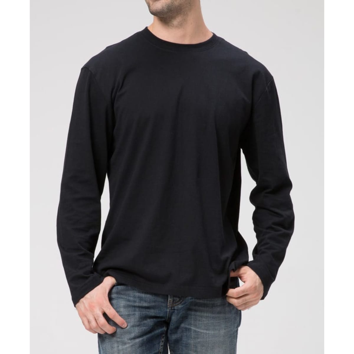 A black long-sleeve tee displayed on a model, paired with denim jeans, featuring a minimalist design.