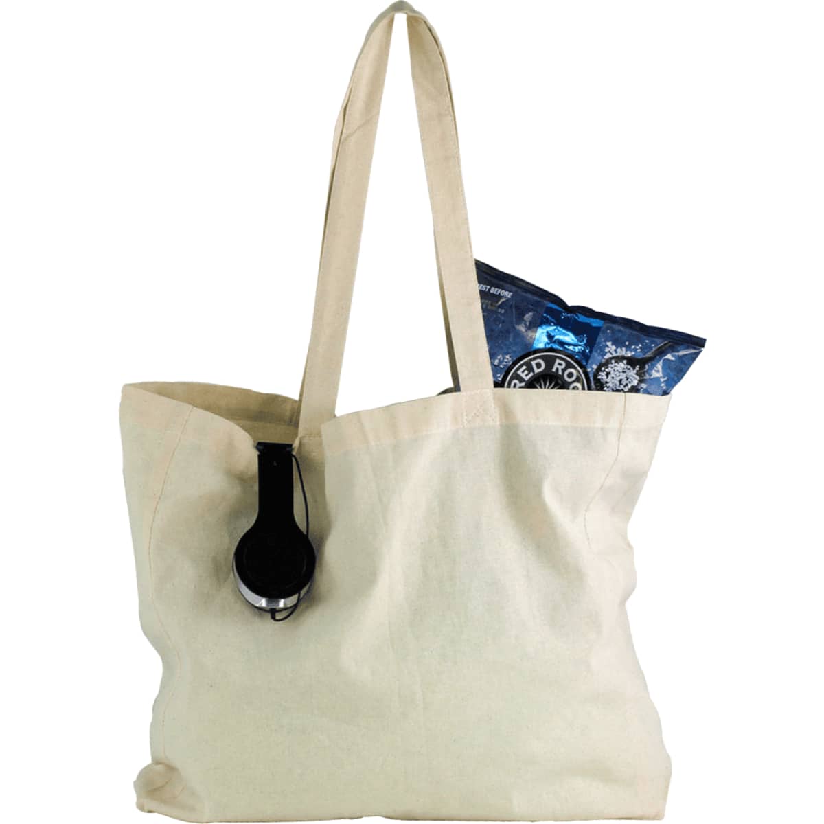 A natural cotton shopper tote in cream, featuring a black headphone and a bag of snacks inside.