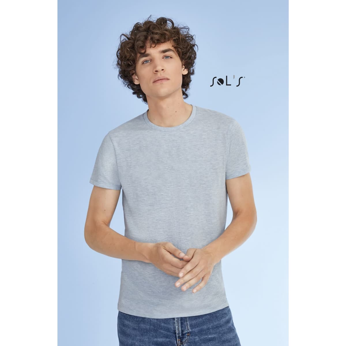 A grey T-shirt made of 100% semi-combed ring-spun cotton, featuring a model with curly hair and a logo.
