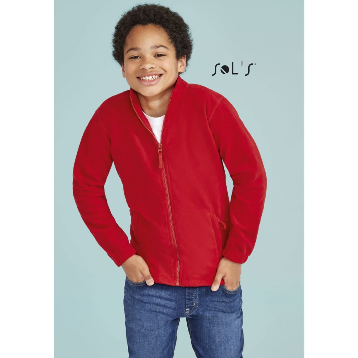 A red fleece jacket with a zip, displayed on a smiling child against a light blue background. It features a logo.