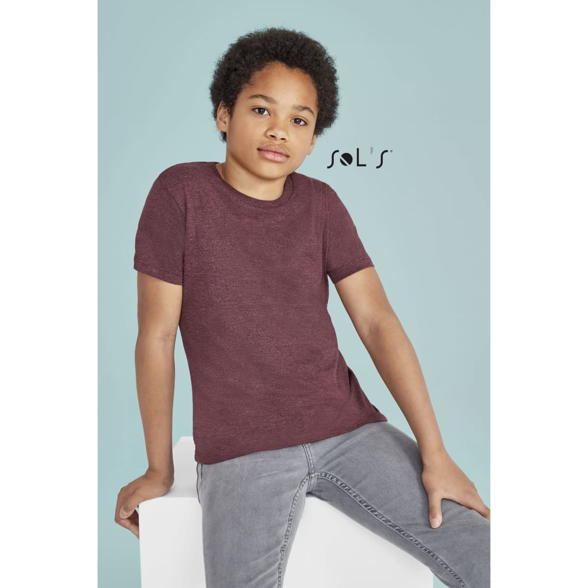 A maroon T-shirt made of 100% semi ring spun combed cotton, featured on a child model against a light background.