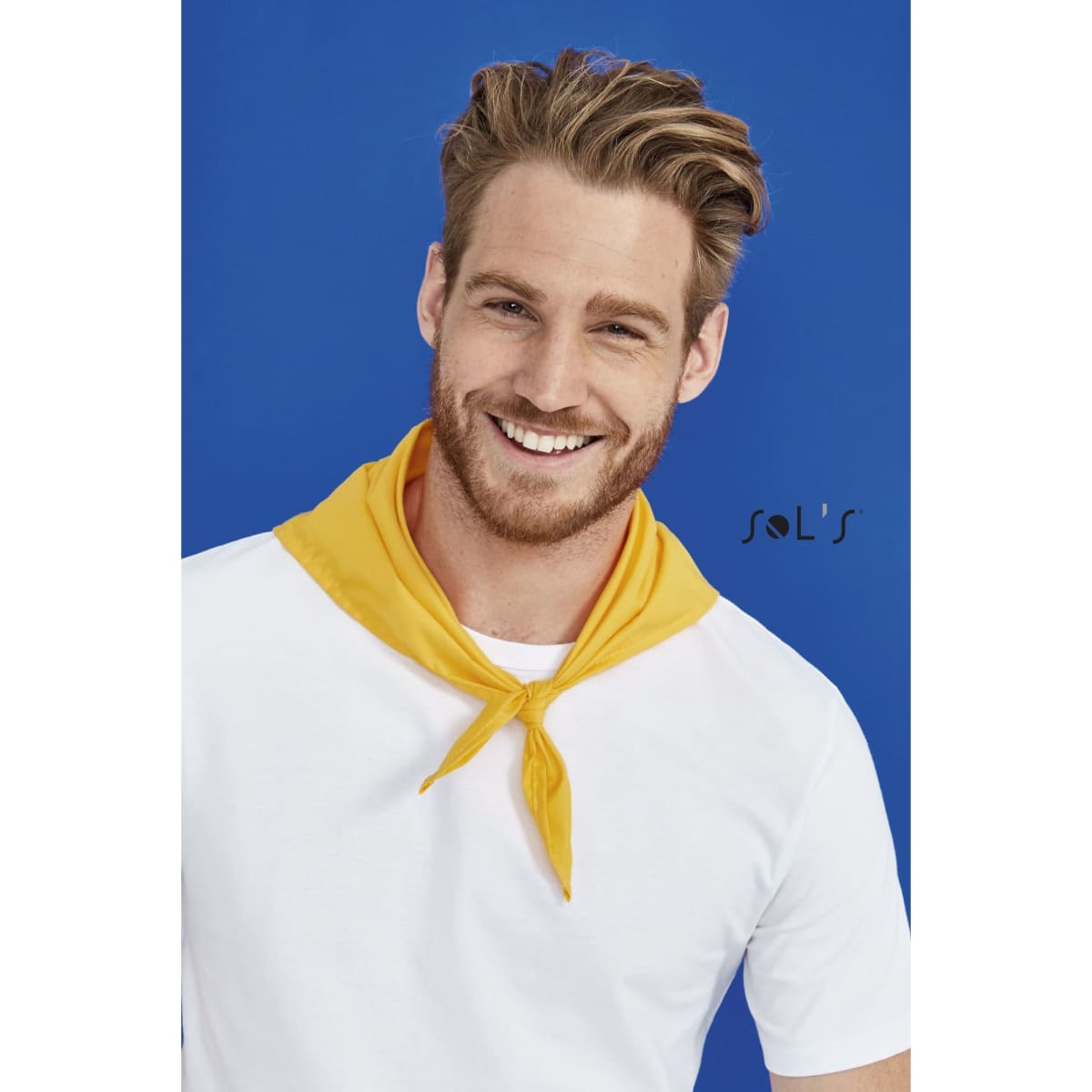A triangular bandana in yellow, 62 x 62 x 87.5 cm, worn around the neck by a smiling man in a white t-shirt.