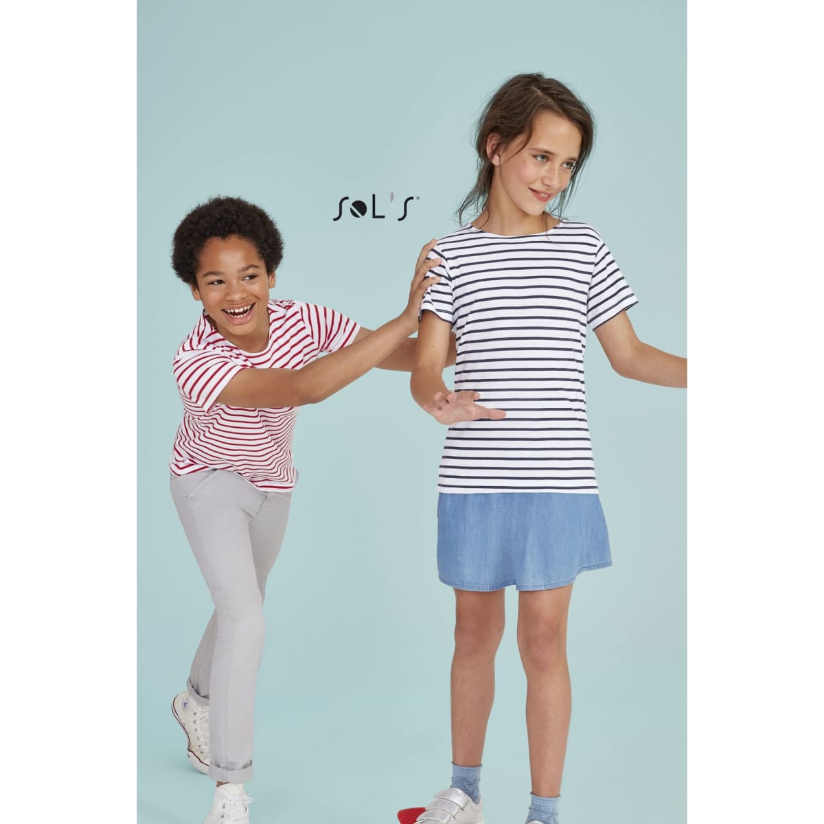 Two kids wearing striped round-neck T-shirts in red and navy blue, standing against a light blue background.