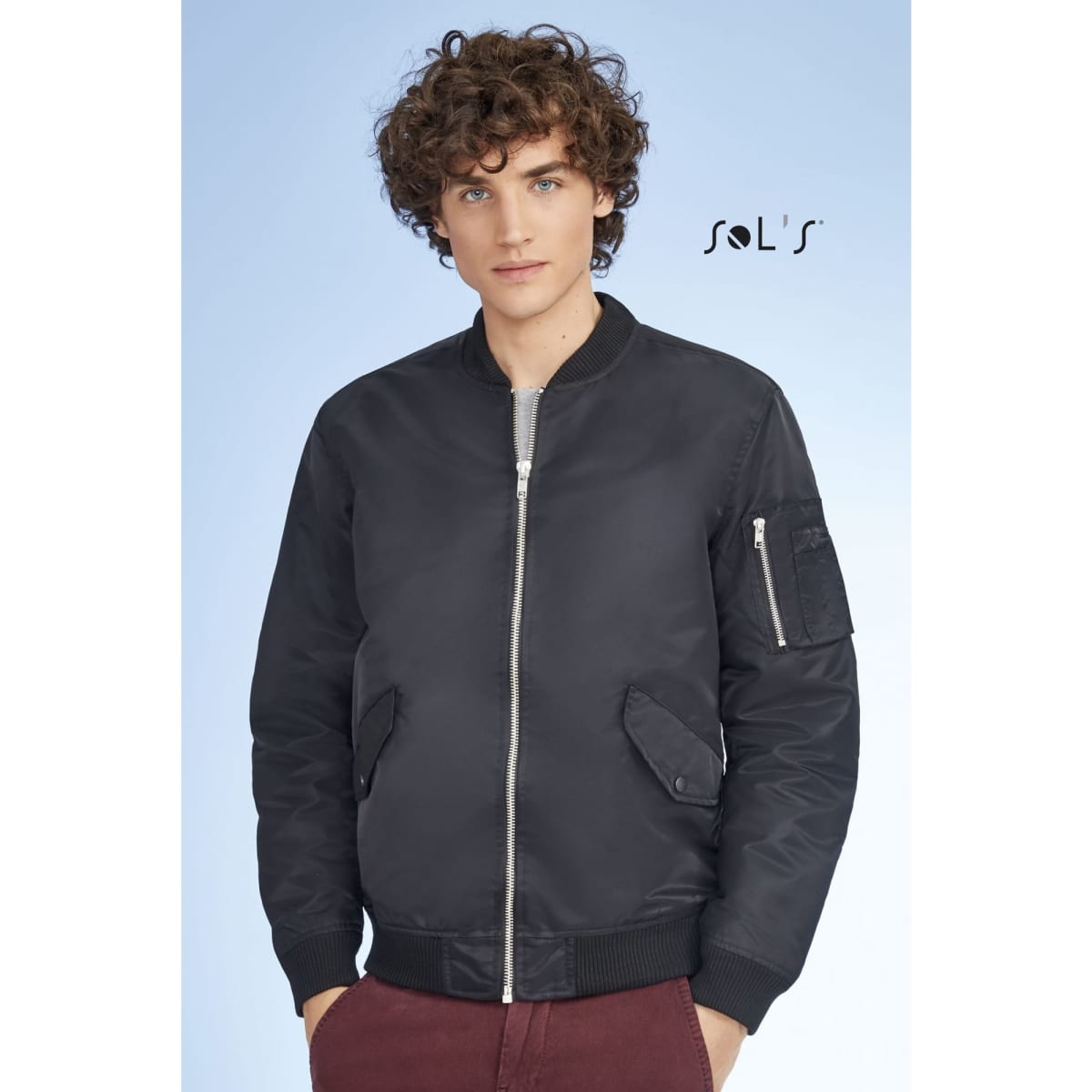 A unisex black bomber jacket with a zip front, side pockets, and a sleeve pocket, featuring a logo.