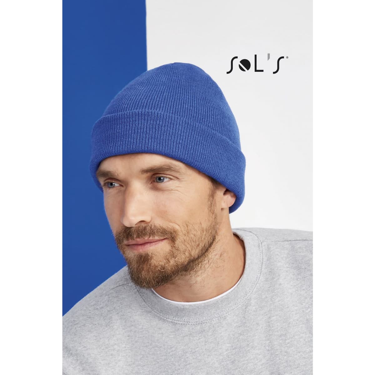 A blue 100% acrylic beanie worn by a man, set against a blue and white background. It features a logo.