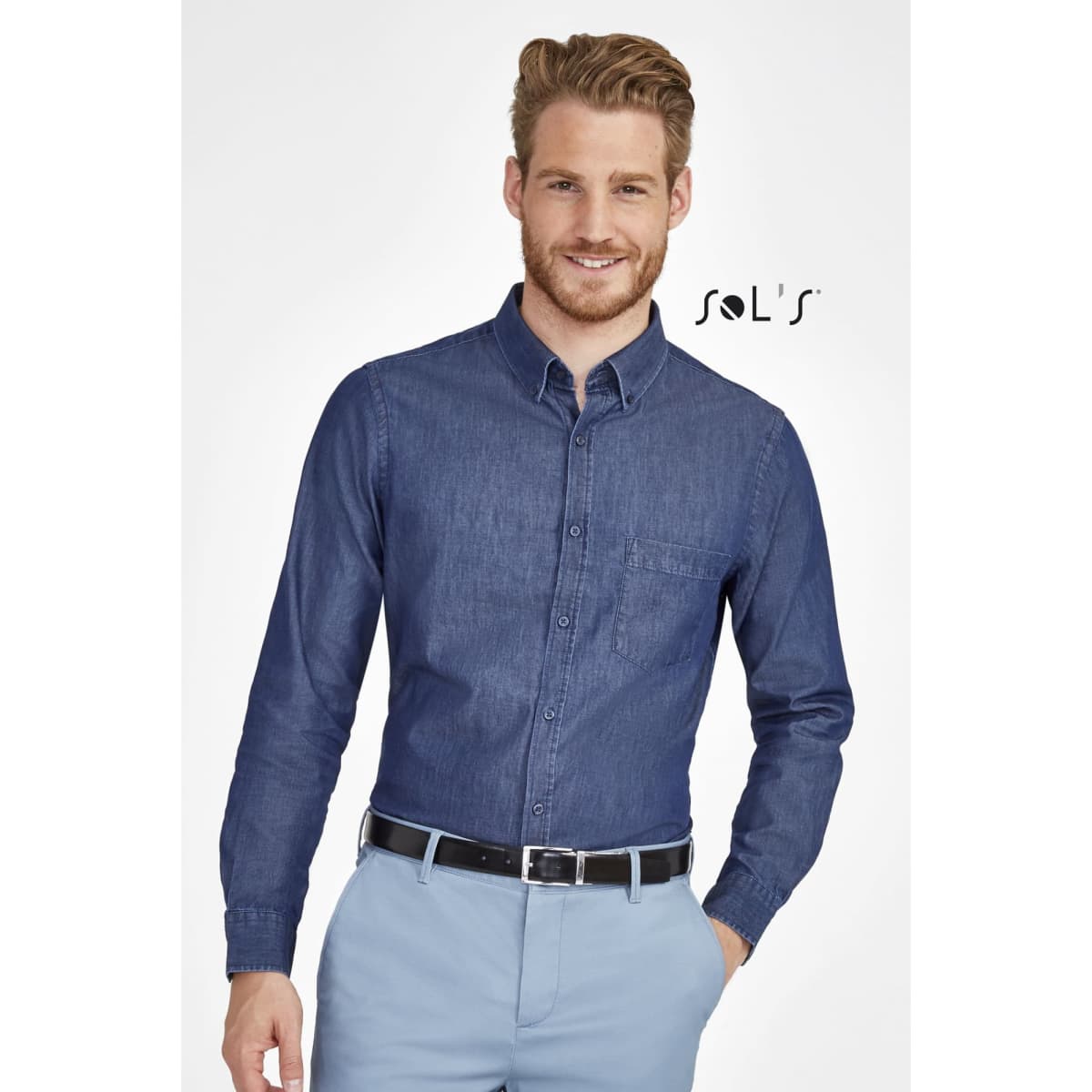 A men's long sleeve denim shirt in dark blue, featuring a button-down collar and a chest pocket. It has branding present.