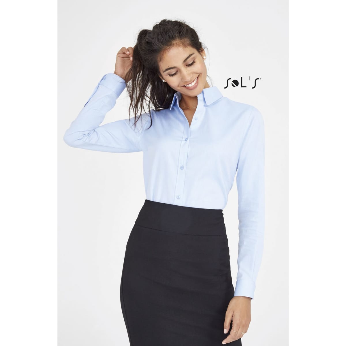 A light blue long sleeve women's herringbone shirt, featuring a collar and buttons, with a logo present.