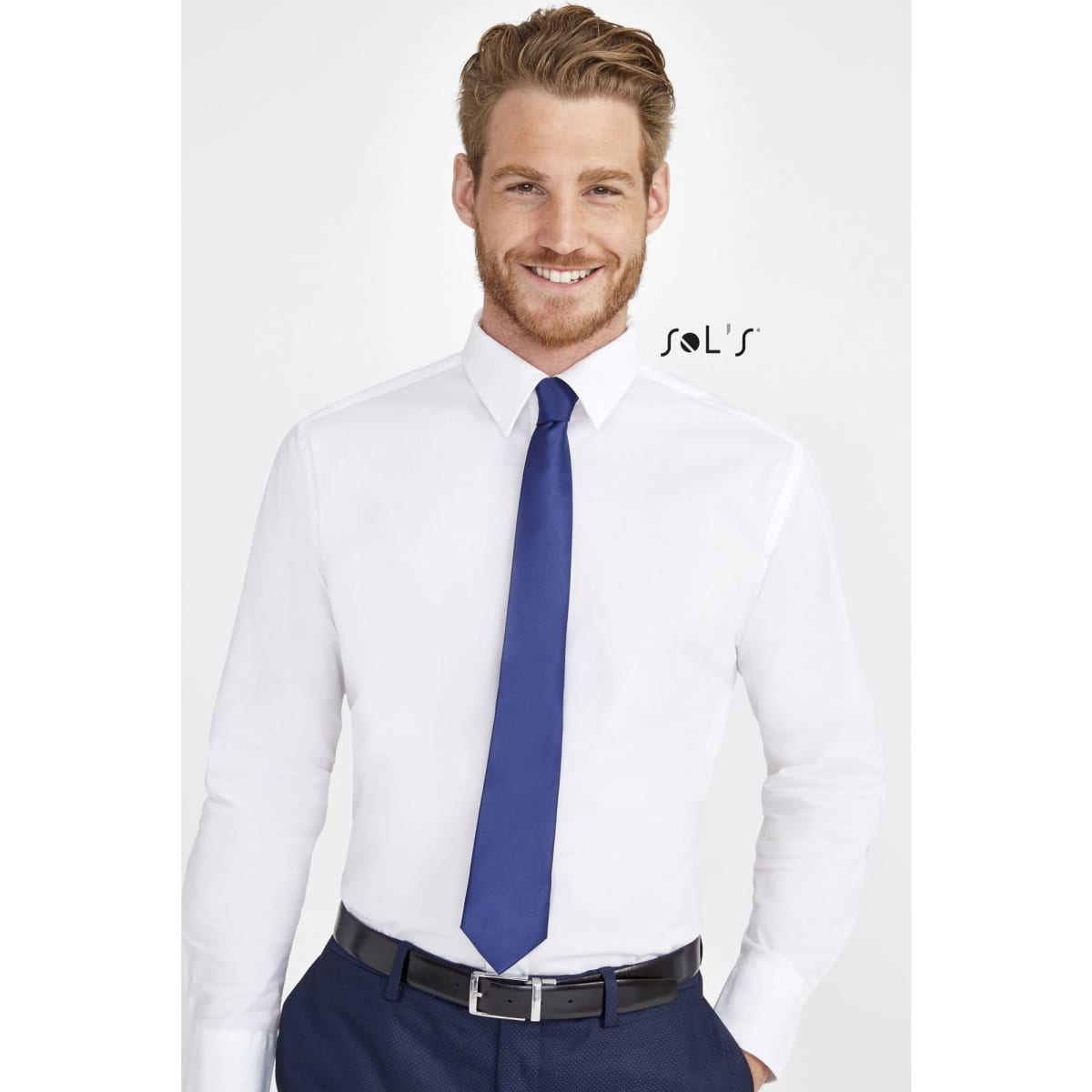 A man wearing a white shirt and a blue tie, smiling against a light background. The image includes a logo.