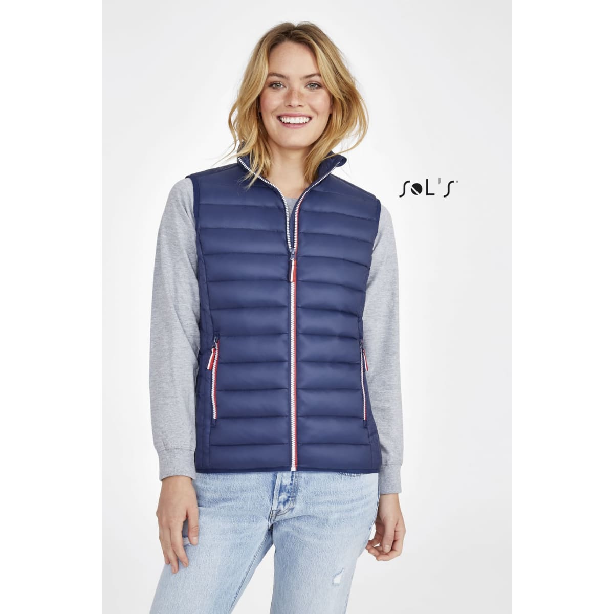 A lightweight women's puffer vest in navy blue with a zip-up front and a grey long-sleeve top underneath.