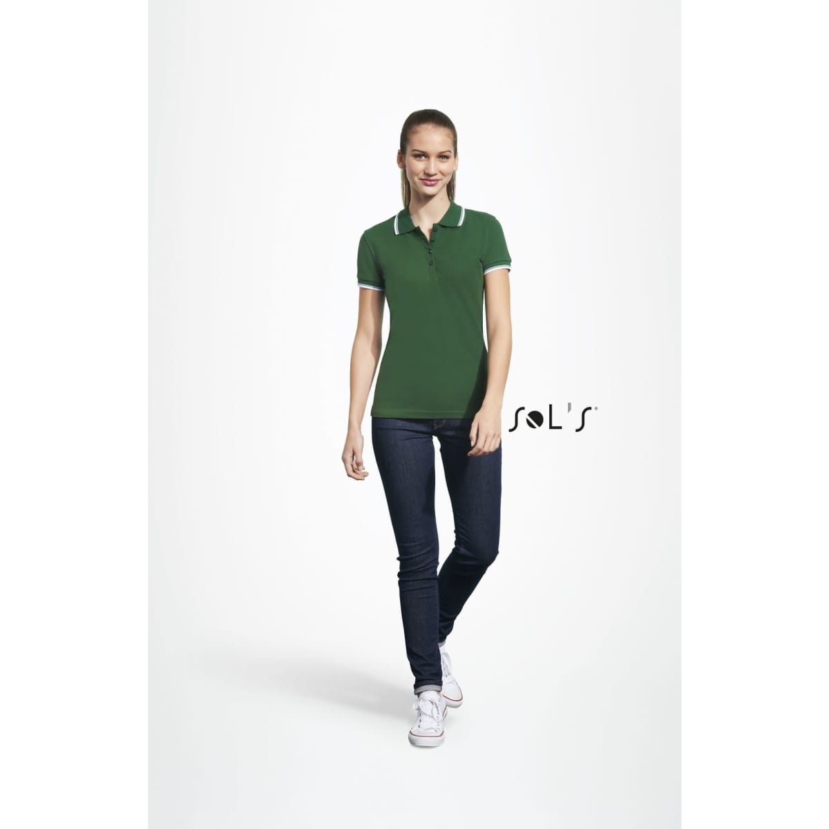 A green women's polo shirt made of 100% combed ring spun cotton, featuring a logo, paired with denim jeans.