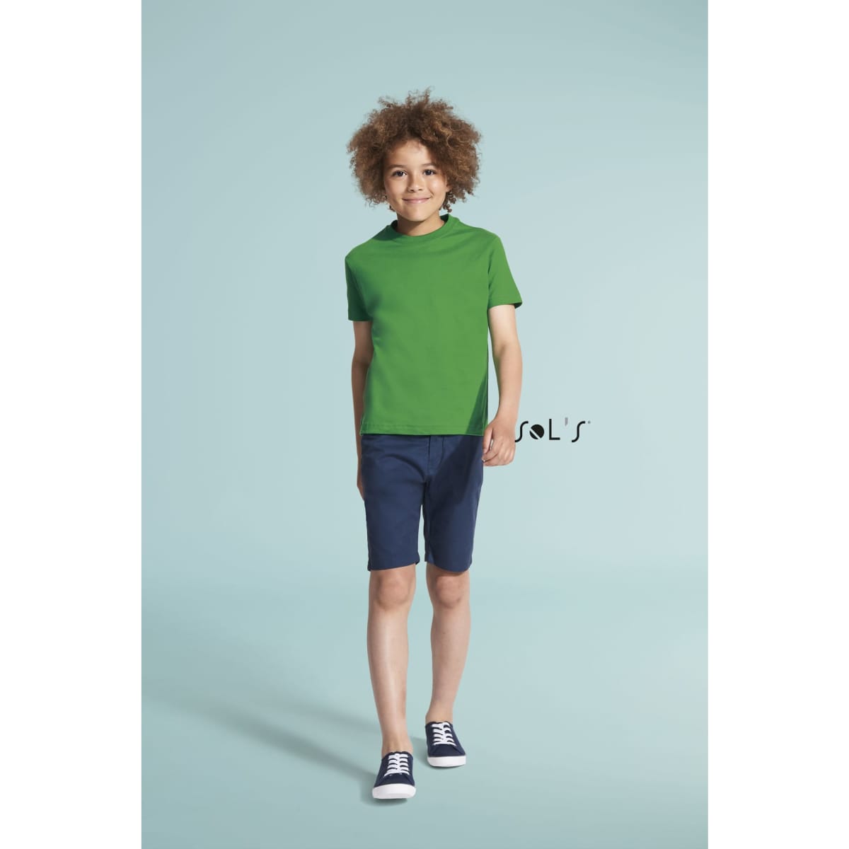 A green round neck T-shirt made of 100% semi combed ringspun cotton, paired with denim shorts and sneakers.