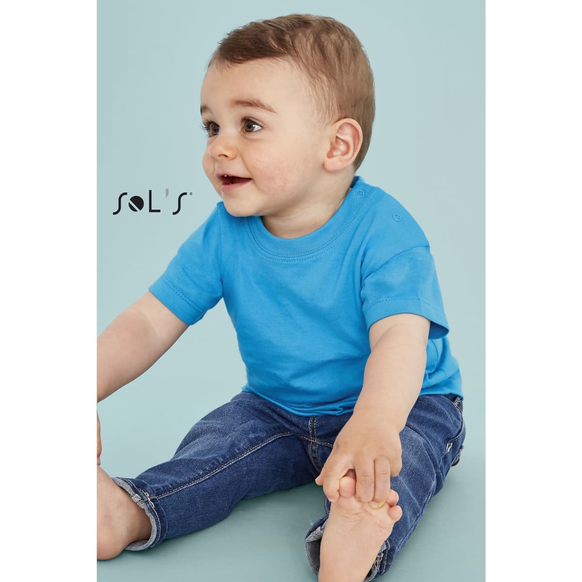 A baby-sized t-shirt in bright blue made from 100% semi-combed ring spun cotton, paired with denim jeans.