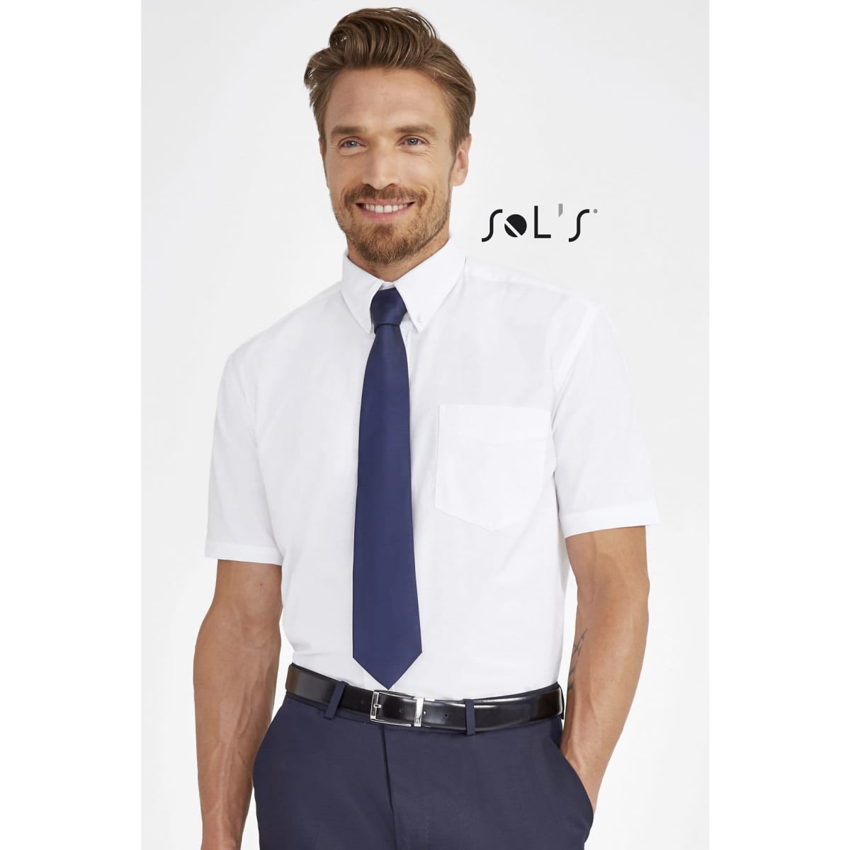 A white short sleeve men’s shirt with a chest pocket, paired with a navy tie. Features branding.